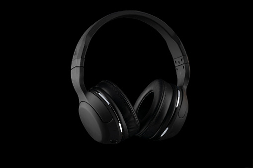 Black wireless headphones isolated on a black background.