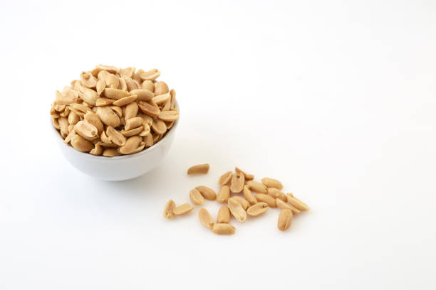 Small bowl of roasted salted peanuts on white background