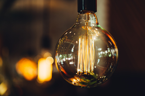 close-up of a round huge light bulb glows in golden color against a dark background in the interior