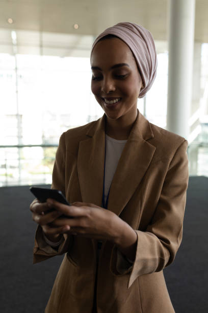 istock Mixed-race businesswoman using mobile phone in office lobby 1138184169