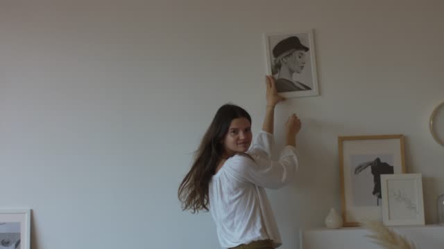 Happy woman decorating house with pictures