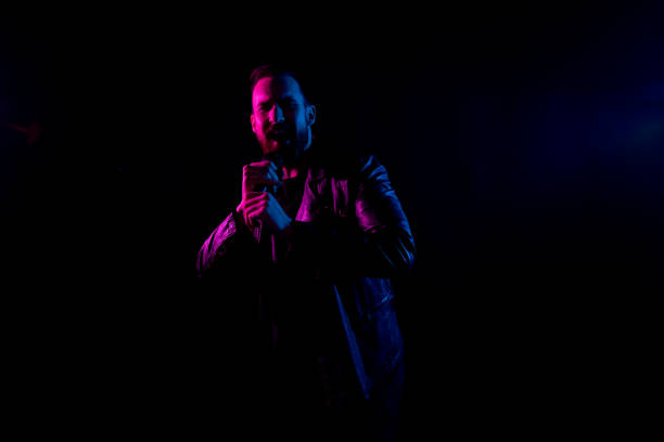 istock Handsome man singing in black background with gel lighting 1138190217