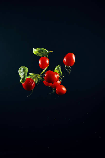 explosión de alimentos con tomates cherry y albahaca - high speed flash fotografías e imágenes de stock