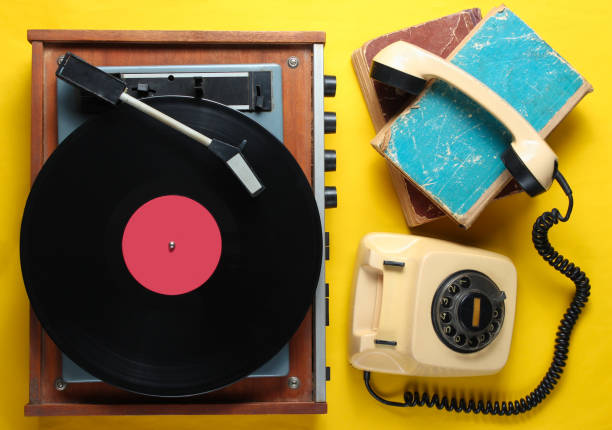istock Old-fashioned objects on yellow background. Retro style, 80s, pop culture. Top view. Vinyl player, rotary phone, old books 1138194111