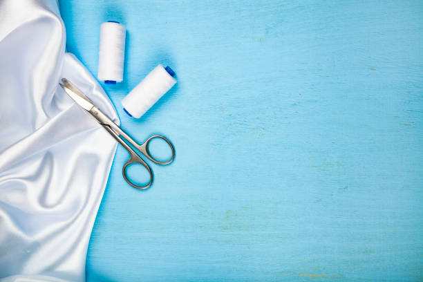 Woman seamstress in the workshop cutting on a table and with scissors the edges of a cut of fabric. Sewing concept.