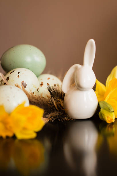 istock Small white rabbit figurine with easter eggs and narcissus 1138197961