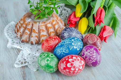 colorful easter eggs, easter cake and tulips on wooden table