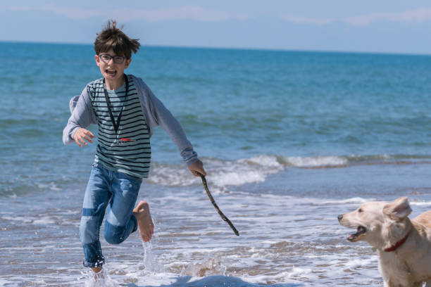 istock Happy boy running wit her dog on the beach. 1138199313