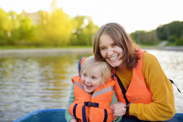 młoda matka i synek pływają łódką po rzece lub stawie w słoneczny letni dzień. jakość czasu rodzinnego razem na przyrodzie. - mother superior zdjęcia i obrazy z banku zdjęć