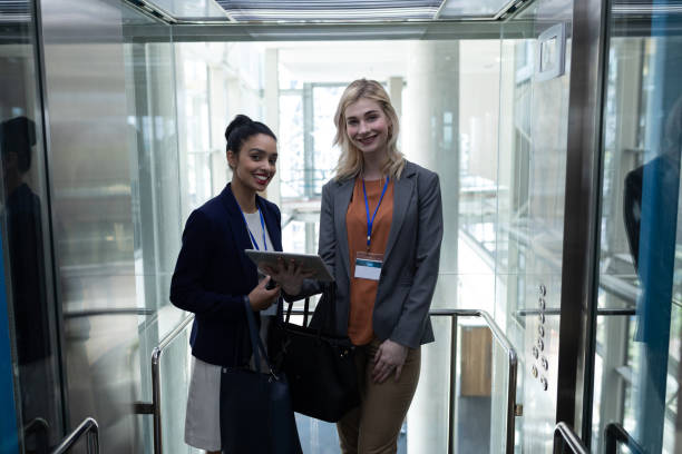 istock Multi-ethnic businesswomen with digital table looking at camera in modern office elevator 1138201584