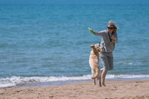istock Happy women playing with her dog at the beach. 1138201638