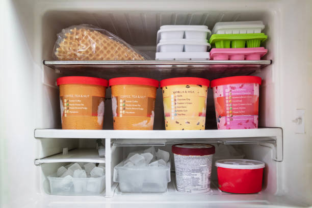 Full of bucket container ice creams flavors and ice cubes in freezer. stock photo