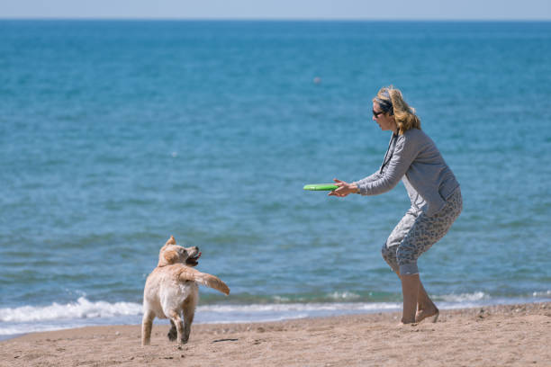 istock Happy women playing with her dog at the beach. 1138201909
