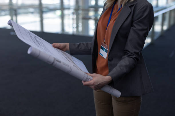 istock Blonde Caucasian female architect holding blueprint in modern office 1138201954