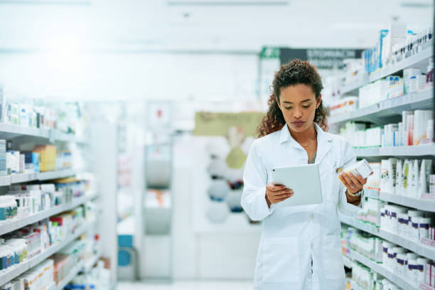 Keeping tabs on her stock Shot of a young woman using a digital tablet while working in a pharmacy prescription medicine stock pictures, royalty-free photos & images