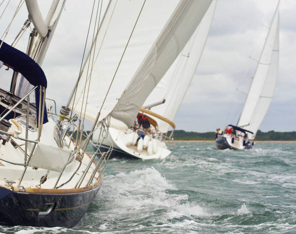 три красивые яхты парусники с белыми парусами гонки близко друг к другу в яркий солнечный день - sailboat sailing sports race yacht стоковые фото и изображения