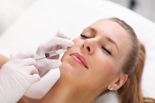 Close up of hands of cosmetologist making botox injection in female lips stock photo