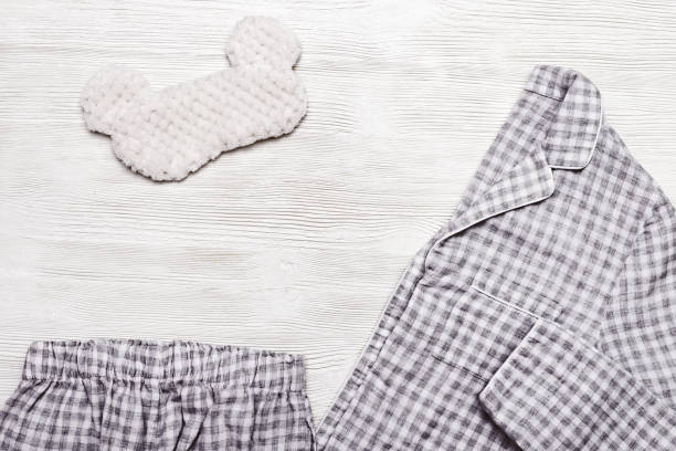 istock Flat lay from warm pants for sleeping, jacket and fluffy mask on light wooden background with copy space. Top view. 1138203260