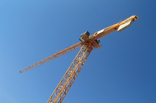Yellow tower crane in front of the bright  blue sky
