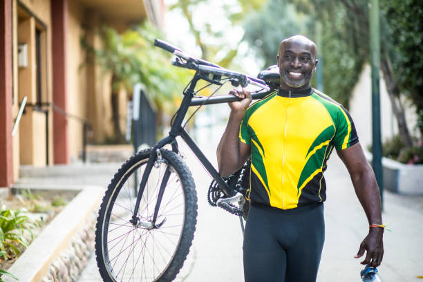 Portrait of a Black Cyclist Carrying Bicycle Portrait of a mature black male cyclist in a jersey cycling vest photos stock pictures, royalty-free photos & images