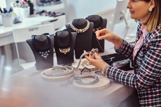 istock Elegantly dressed woman makes handmade necklaces, working with needles and thread in workshop. 1138206471