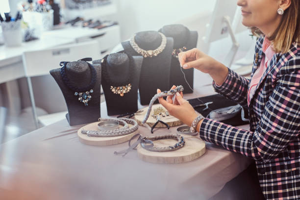 istock Elegantly dressed woman makes handmade necklaces, working with needles and thread in workshop. 1138206511