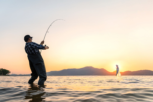 A young boy enjoys fishing for bass early in the morning while on vacation.