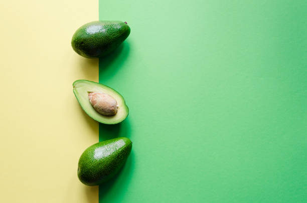 Organic avocado on color background Organic avocado with seed and whole fruits on color yellow and green background. Pop art design, creative summer food concept. Green avocadoes pattern in minimal flat lay style. Top view. Copy space. pop art photos stock pictures, royalty-free photos & images