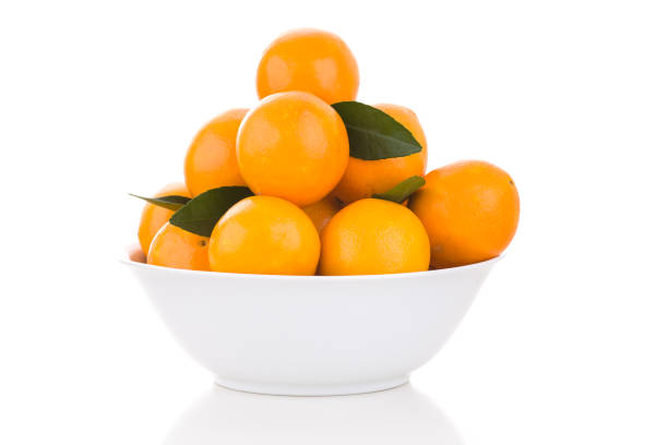 White bowl with oranges and leaves stock photo
