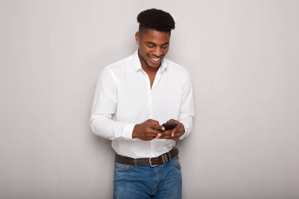istock smiling young african man looking at cellphone against by background 1138213104