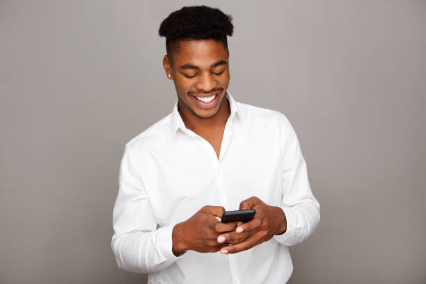 istock happy young black man looking at mobile phone by gray wall 1138213131