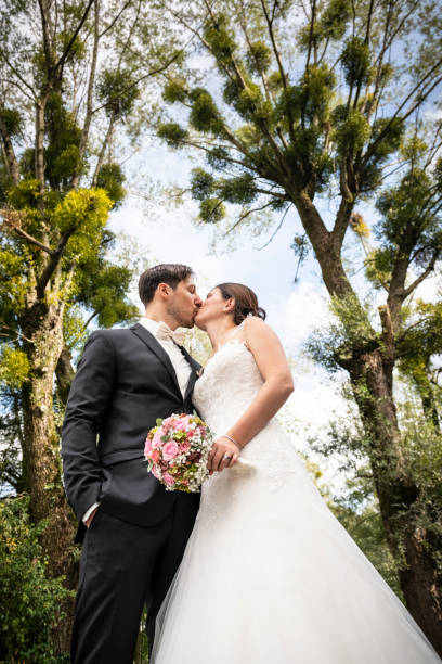 istock Just married bride and groom kissing under mistletoes 1138214024
