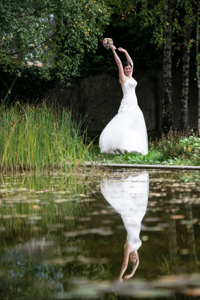 Happy bride jumping in the park with her hands up