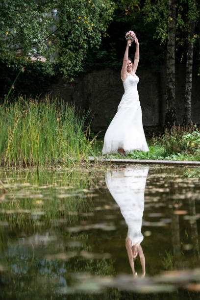 istock Happy bride jumping in the park with her hands up 1138214040