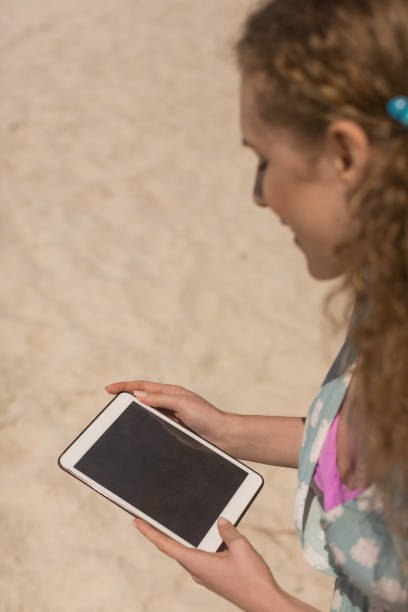 istock Young Caucasian woman using digital tablet at beach 1138216259