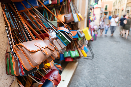Rome, Italy many leather purse bags vibrant colors hanging on display in shopping street market in Roma city
