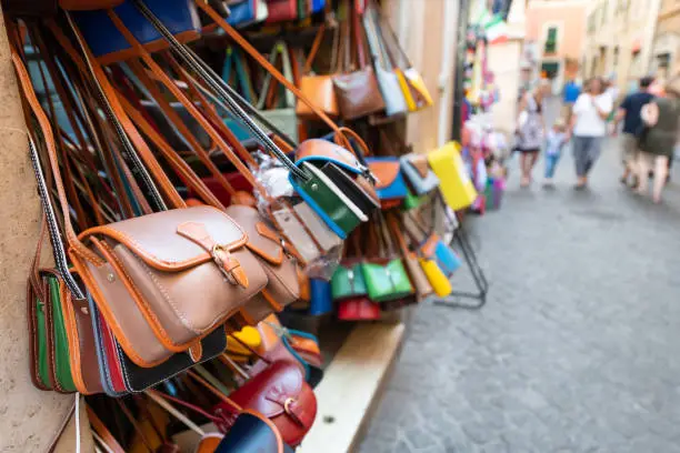 Photo of Rome, Italy many leather purse bags vibrant colors hanging on display in shopping street market in Roma city