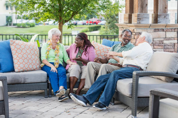 Two older couples hanging out on patio, conversing A multi-ethnic group of mature and senior friends hanging out together, sitting outdoors on a patio conversing. The African-American couple are in their 50s. The Caucasian couple are in their 70s. The women are sitting next to each other, talking, and the men are chatting with each other. 55 59 years stock pictures, royalty-free photos & images