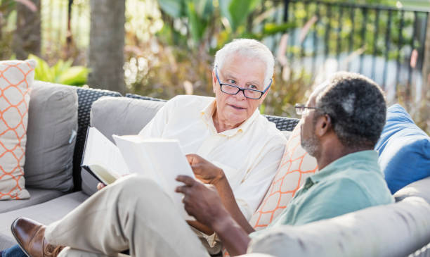 istock Retired men sitting on patio reading books, conversing 1138224976