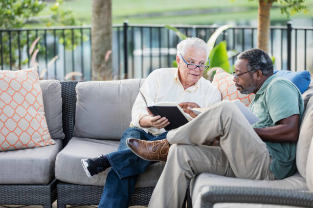 Retired men sitting on patio reading books, conversing