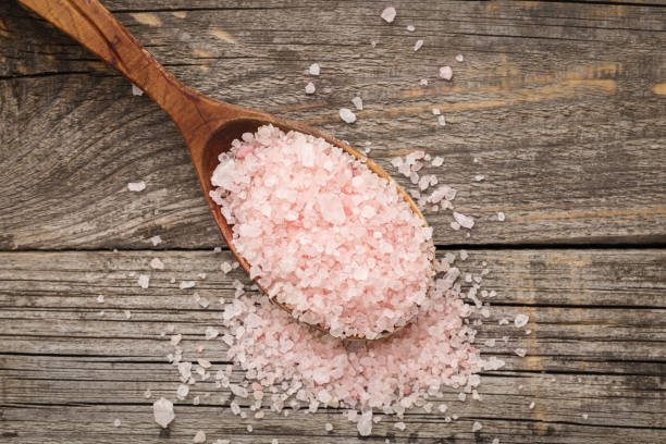Pink salt in wooden spoon on wooden table. Top view Pink salt in wooden spoon on wooden table. Top view bath salt photos stock pictures, royalty-free photos & images