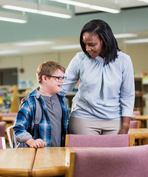 istock Teacher and boy with down syndrome in school library 1138226836