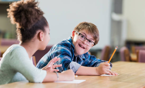 istock Boy with down syndrome, classmate, writing in school 1138227839