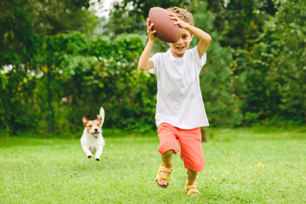 kind spielt amerikanischen fußball bereit, touchdown und hund jagt ihn - child american football football sport stock-fotos und bilder