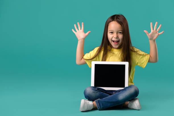 little girl holding a blank tablet computer - child computer laptop little girls imagens e fotografias de stock
