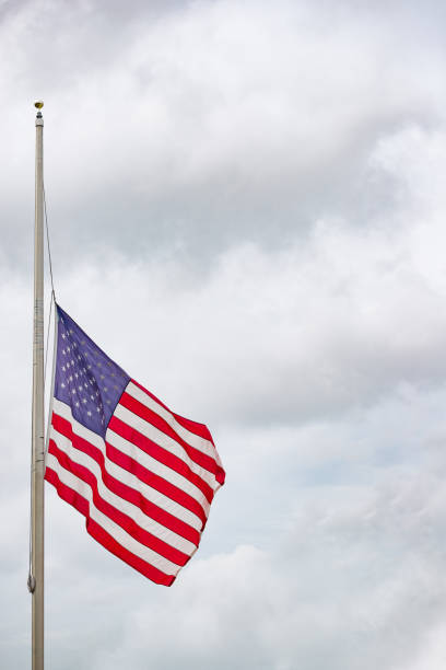 istock American flag flying at half mast or half staff against cloudy sky 1138231027