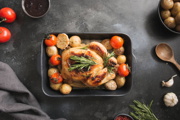 istock Roasted chicken with potatoes, tomatoes on black vintage table. View from above. 1138231236
