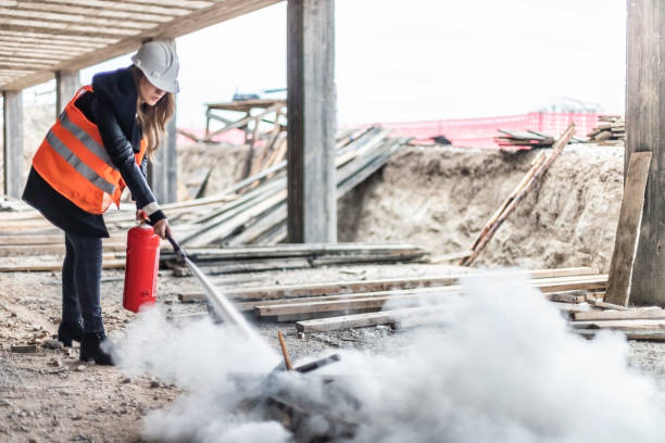 Female rescue worker with a fire extinguisher on construction site Female rescue worker with a fire extinguisher  on construction site fire hose photos stock pictures, royalty-free photos & images