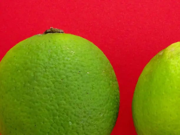 Close-up of two Isolated limes on a redbackground
