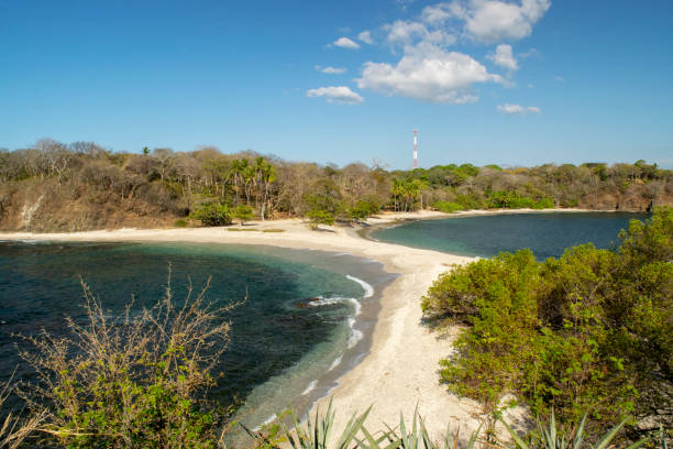 San Juanillo Beach Beach in Guanacaste, Costa Rica where two bays come together leaving a thin white sand beach strip in the middle tidal inlet stock pictures, royalty-free photos & images
